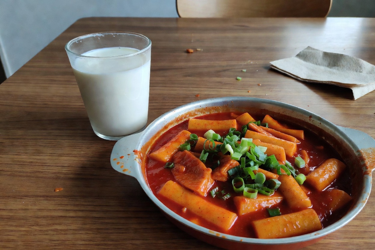 떡볶이 옆에 놓인 우유 한 잔